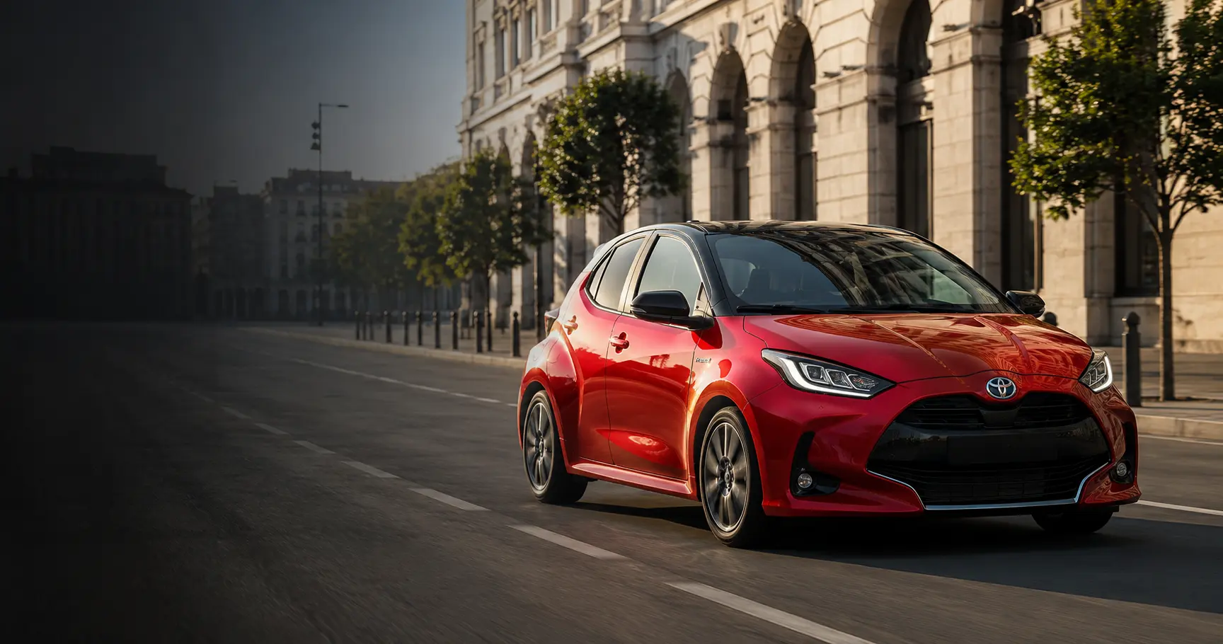 Piros Toyota Yaris Hybrid modern városi környezetben